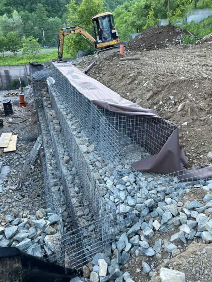Gabion retaining wall under construction with an excavator